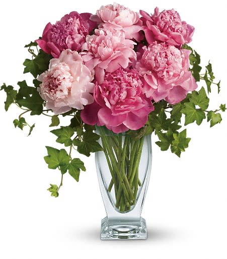 Pink peonies arranged in a clear glass vase with trailing ivy