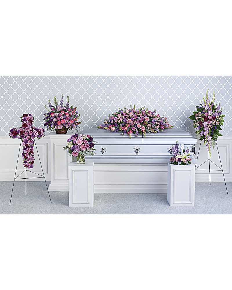 Funeral casket surrounded by pink and purple floral sprays
