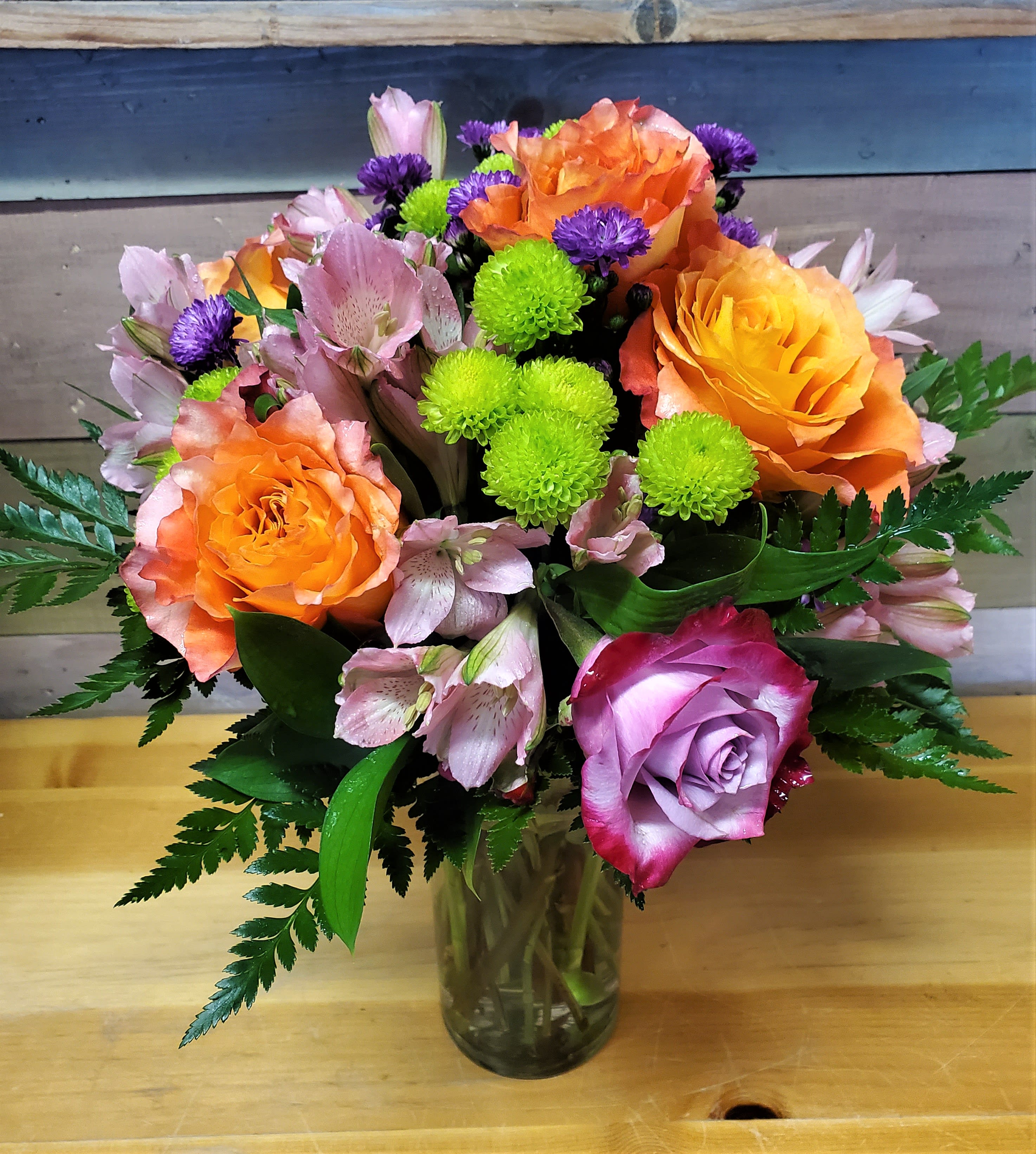 Mixed bouquet of orange and lavender roses with pink alstroemeria in a glass vase