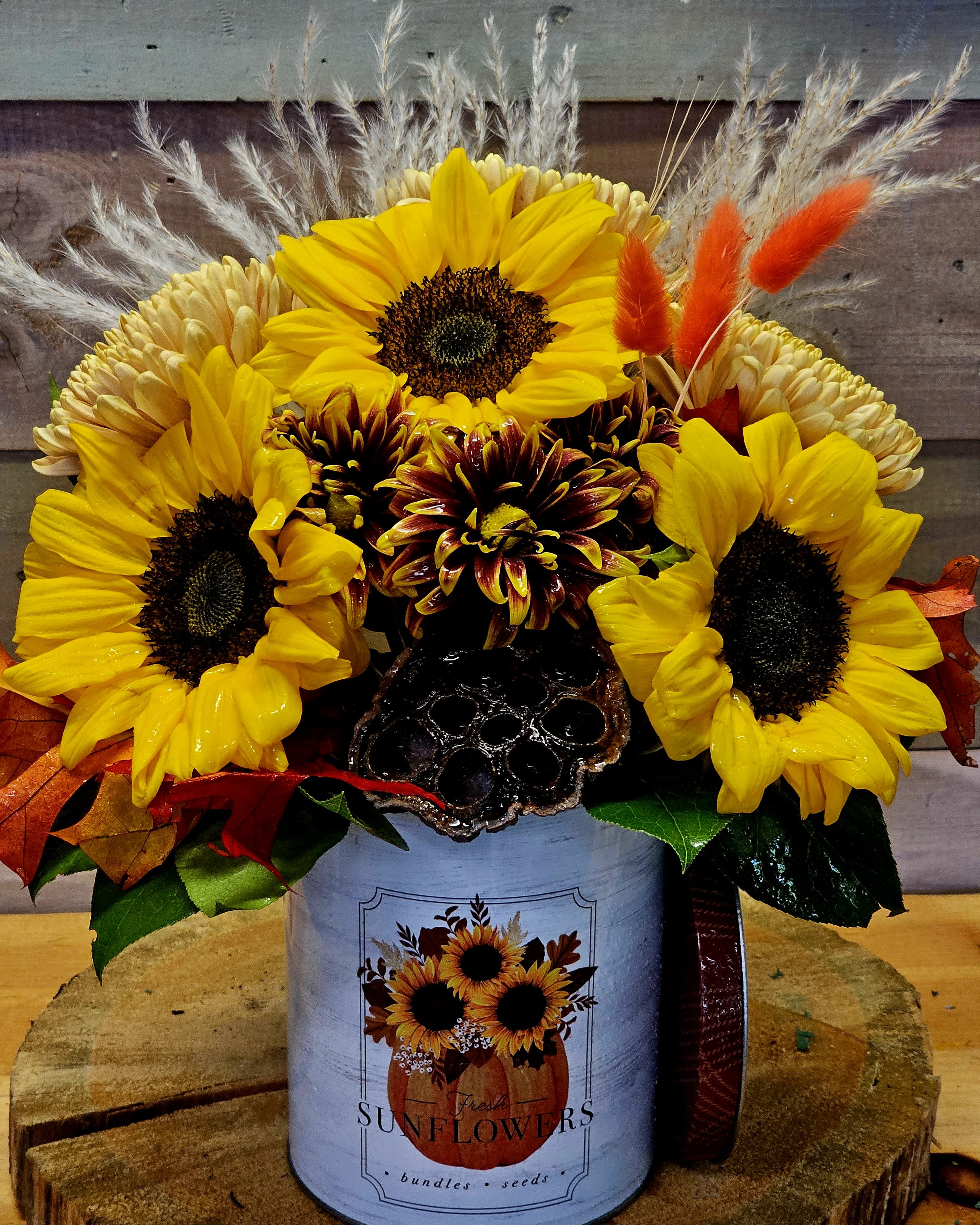 Fall in Love - The arrangement comes in a food safe tin. Use it again once your flowers are no good. Sunflowes, dried wheat, dasies. * All flowers are subject to change along w color. *