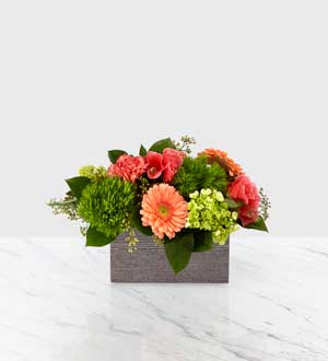 Mixed bouquet in a gray rectangular container with pink, coral, and green blooms