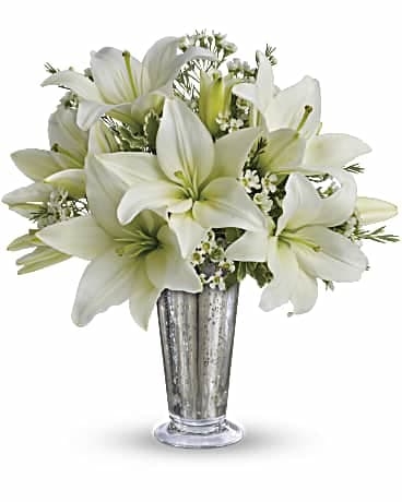White lilies arranged in a tall silver vase