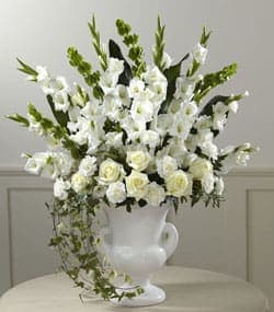 Fond Reflections Arrangement  - An expression of sympathy that’s tasteful dignified and with a beautiful sensibility that conveys your feelings with warmth and sincerity. This generously-scaled arrangement makes a superb choice with hand-selected white gladioli carnations roses and Bells of Ireland complemented with lush greenery and arranged in a classic white ceramic urn.   Its comforting presence and impressive scale makes a fitting tribute for a wake the funeral service or to add a note of serene consolation to a graveside service.