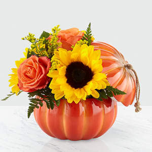 Harvest Traditions Pumpkin - Our Harvest Traditions ceramic pumpkin vase has a stem and jute handle that can be reused all season long; it is filled with a collection of truly gorgeous blooms. Comprised of an array of orange roses, bold sunflowers and peach hypericum berries, this arrangement is sure to add a flare of harvest delight to any room. 