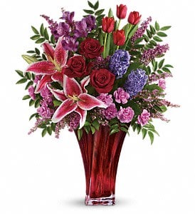 One Of A Kind Love Bouquet  - For a love that's truly one of a kind. Celebrate your unique bond this Valentine's Day with this magnificent bouquet of roses, lilies, alstroemeria and more, artfully arranged in an elegant red blown-glass vase. Dazzling with graceful details, it's a true décor piece they'll enjoy forever as a resplendent reminder of your love.  Red roses, red tulips, pink stargazer lilies, purple alstroemeria, pink miniature carnations, and lavender hyacinth are arranged with pink heather, huckleberry and lemon leaf. Delivered in a gorgeous Love's Passion vase. 
