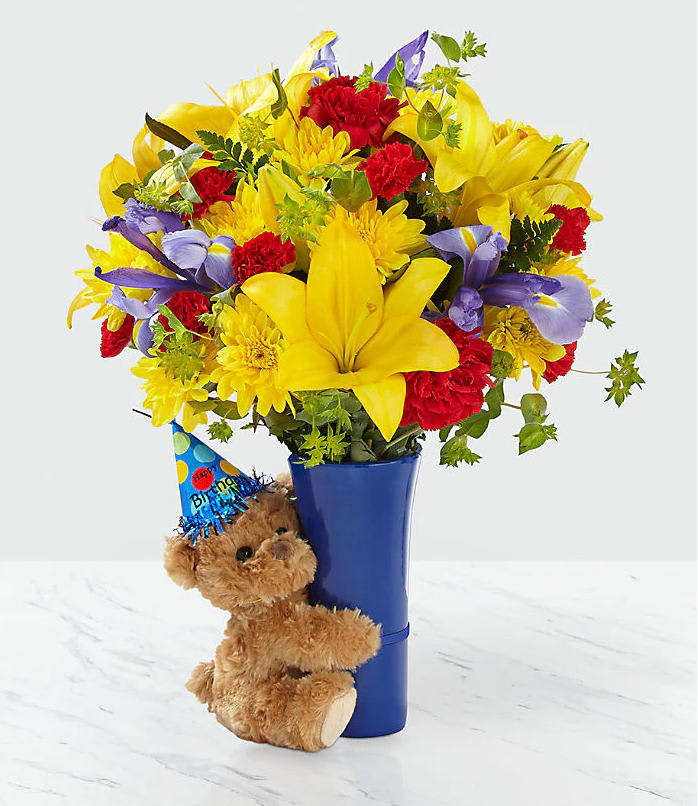 Bouquet of yellow, red, and purple flowers in a blue vase with a teddy bear