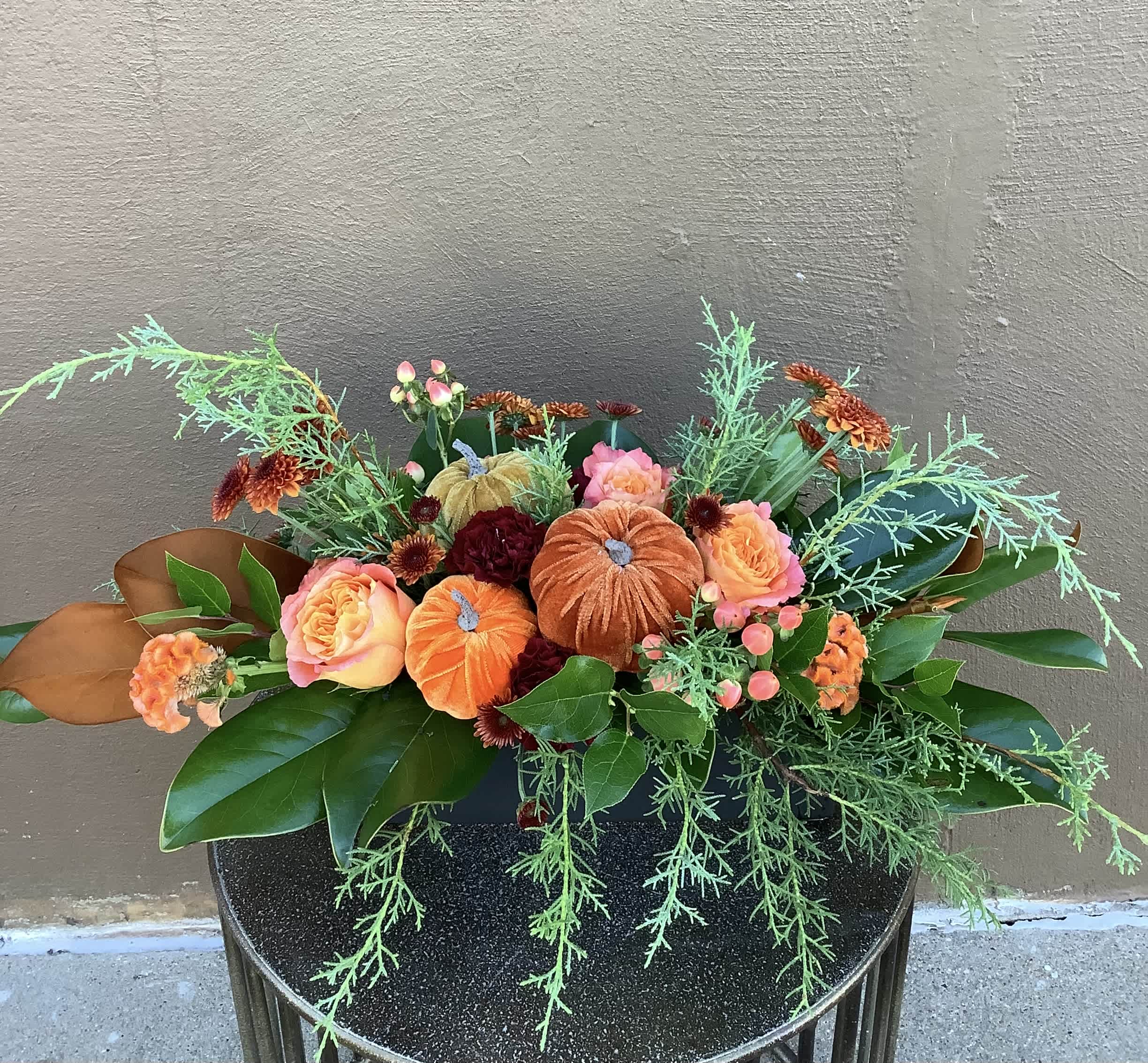 Fall Gathering - This arrangement is a perfect addition to any fall gathering. Orange-tone roses, bronze button mums, fall carnations, three cute pumpkins nestled in the center, accented with beautiful fall foliages. 