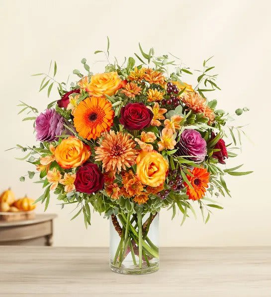 Fall Grandeur - All-around arrangement with red roses, autumn-colored roses and daisy poms, orange Gerbera daisies and Peruvian lilies (alstroemeria), bronze mums, purple kale; accented with burgundy hypericum berries, assorted eucalyptus, assorted greenery and feather willow.