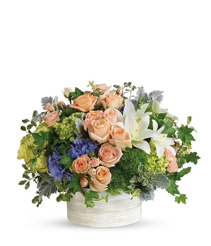 Peach roses and white lilies in a white round container