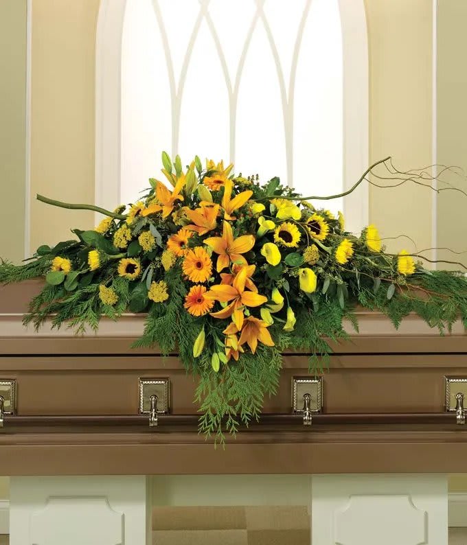 Yellow and orange floral casket spray with lilies and sunflowers