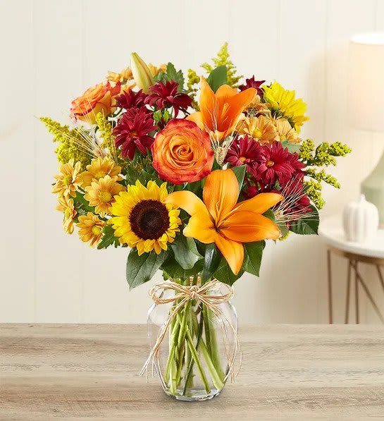 Fields of Europe for Fall - Product ID: 90831  Imagine spending a brisk Autumn day browsing the bustling flower markets of Europe. It's easy with our bestselling arrangement of orange roses and lilies, vibrant sunflowers, poms and more, hand-gathered in a classic glass vase and finished off with charming raffia ribbon. They'll cherish it like a keepsake from a trip they've yet to take. Roses, sunflowers, lilies, daisy poms, solidago and salal, accented with dried fall leaves Artistically designed by our florists in a stylish glass gathering vase tied with raffia; vase measures 8"H Large arrangement measures approximately 21"H x 17"L Medium arrangement measures approximately 20"H x 15"L Small arrangement does not include roses and measures approximately 17"H x 13"L Lilies may arrive in bud form and will open to full beauty over the next 2-3 days Our florists hand-design each arrangement, so colors, varieties and container may vary due to local availability