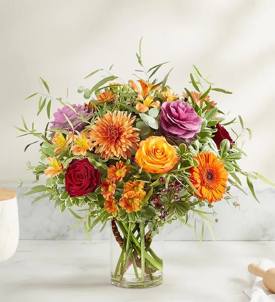Fall Splendor - An abundant, garden-inspired mix of blooms is gathered with natural accents inside a clear glass vase. It’s a gift guaranteed to make a grand impression at every gathering.