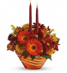 Orange and red floral centerpiece with two burgundy candles in a striped bowl