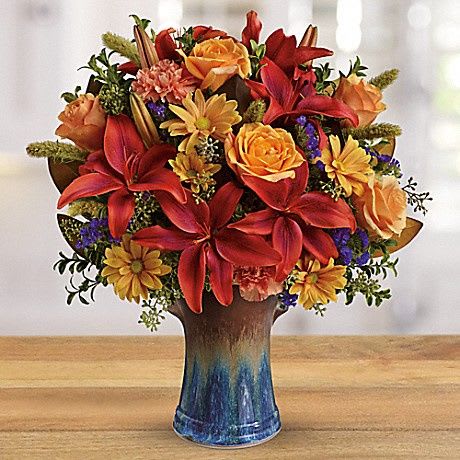 Mixed bouquet of red and orange flowers in a blue vase