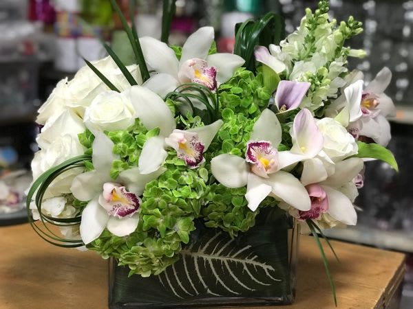 White orchids and roses in a black square vase