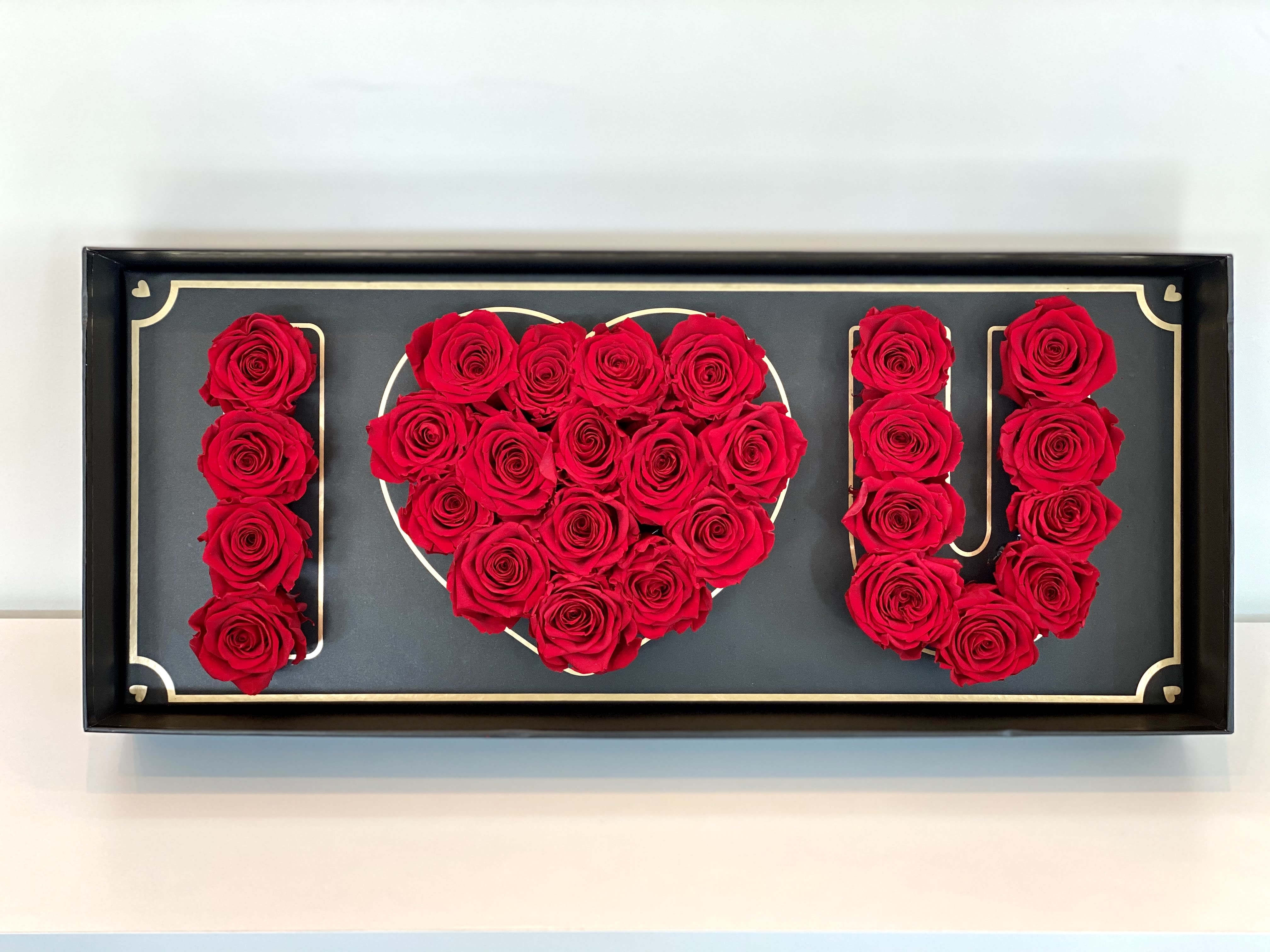 Red roses arranged to spell "I ♥ U" in a framed display