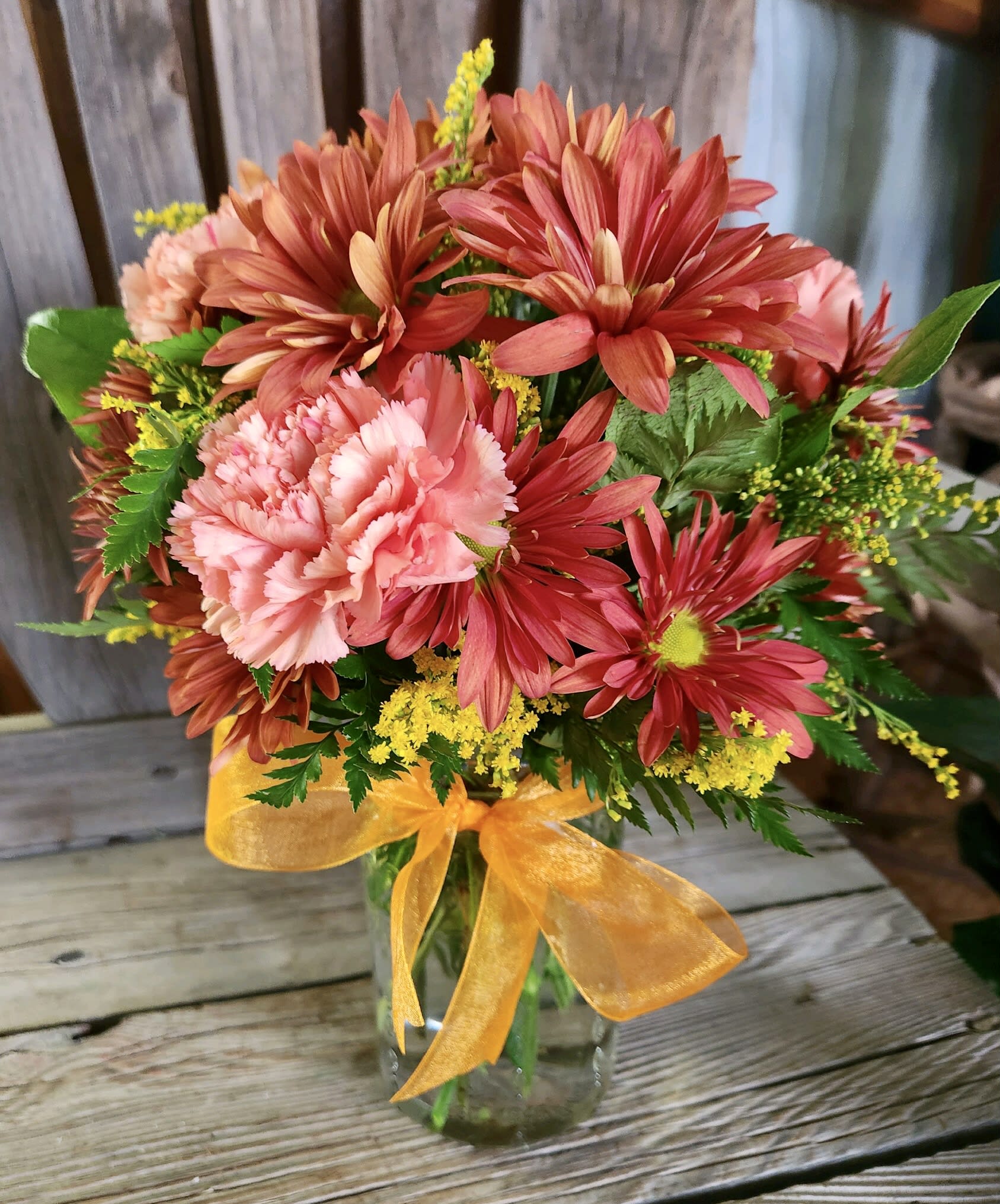 Pink and red mixed bouquet in a glass vase with a yellow ribbon