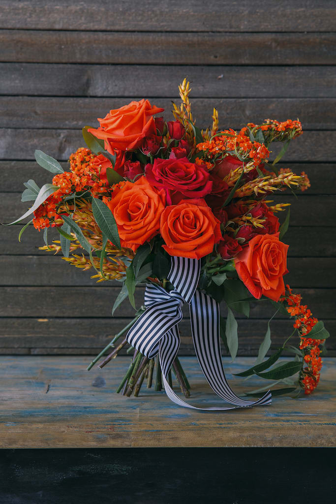 Bouquet of orange and red roses with a striped ribbon