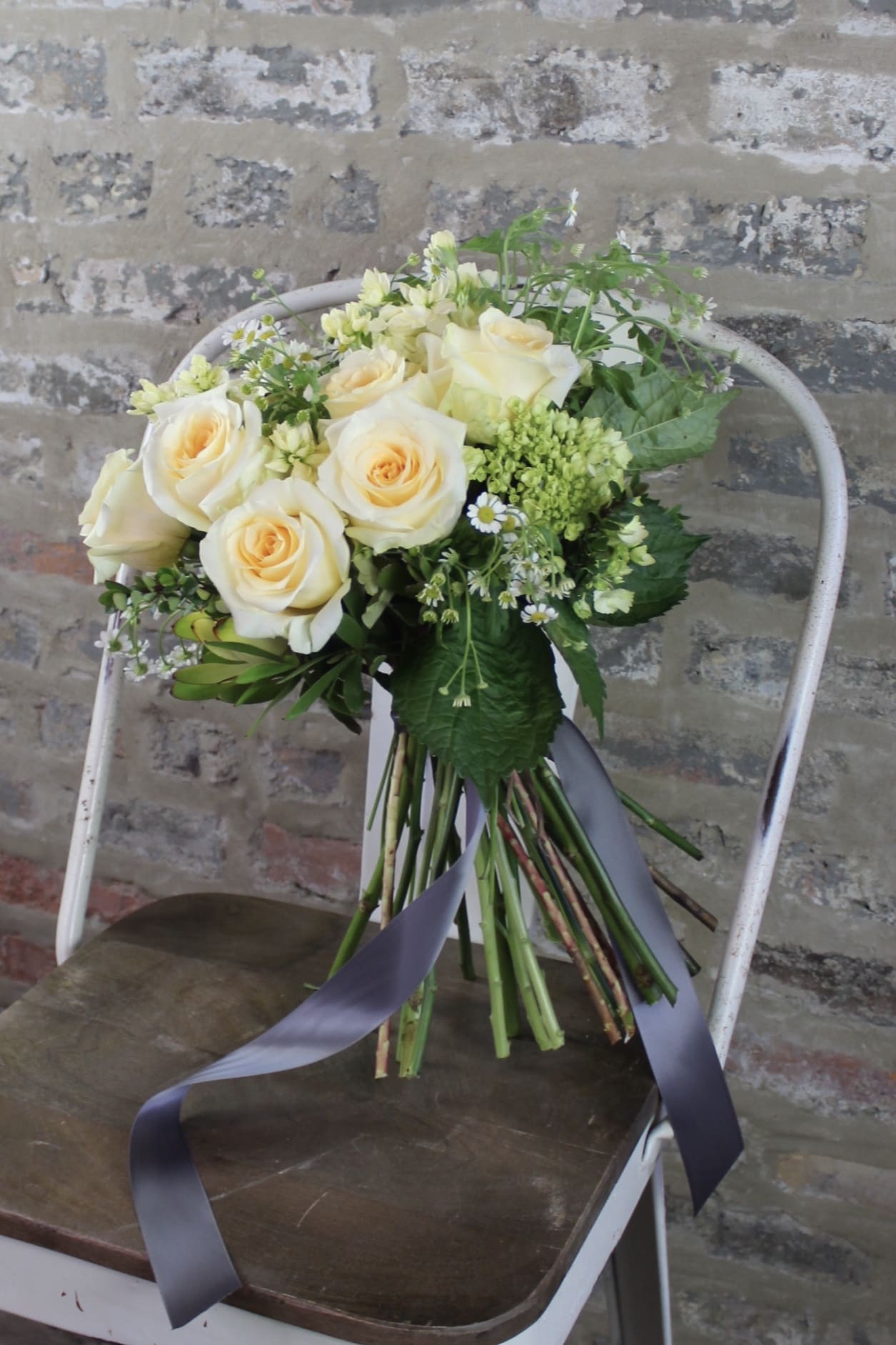 Bouquet of cream roses with small white filler flowers and a ribbon