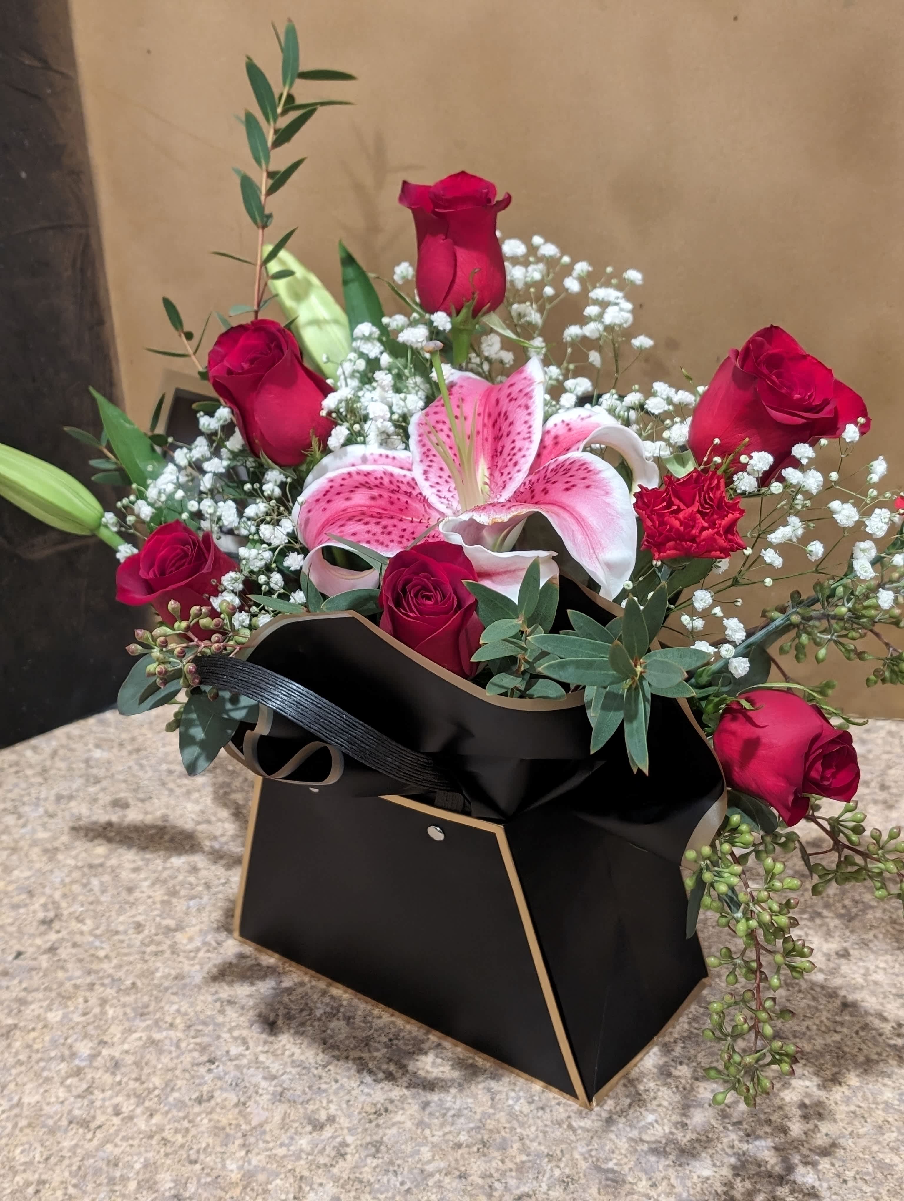 Bouquet of red roses and a pink lily in a black box