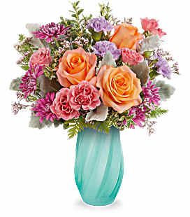 Bouquet of peach roses and pink mixed flowers in a turquoise vase