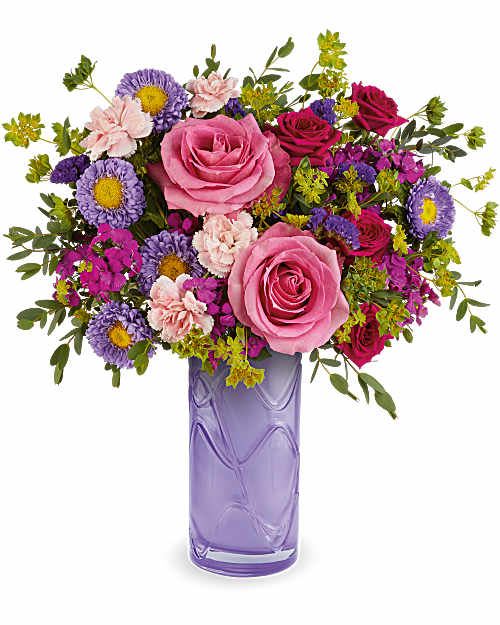 Pink and purple mixed bouquet in a lavender glass vase