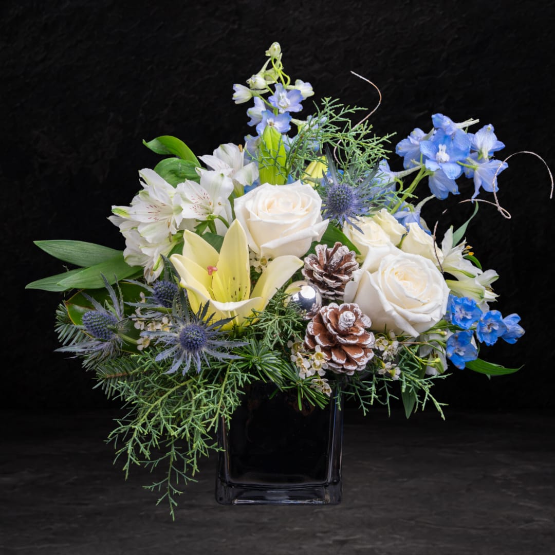 White roses and lilies with blue flowers in a black vase