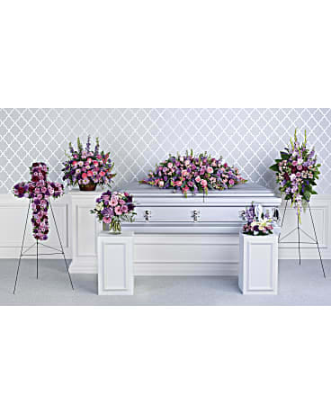 Funeral casket surrounded by pink and purple floral sprays