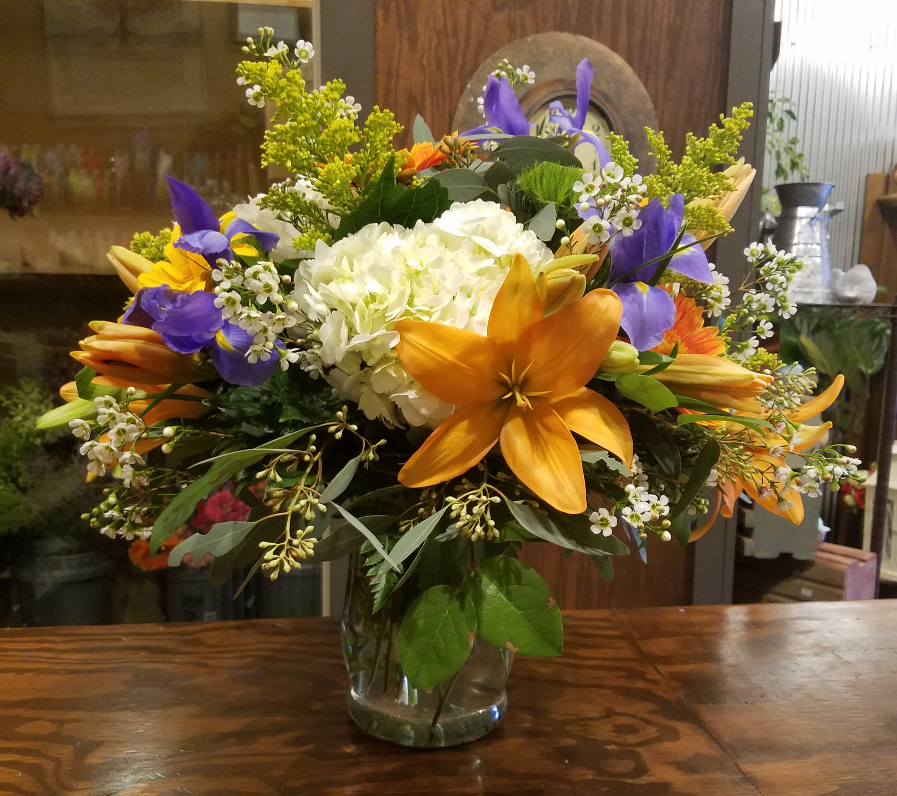 Mixed bouquet in a clear glass vase with orange lilies and purple irises