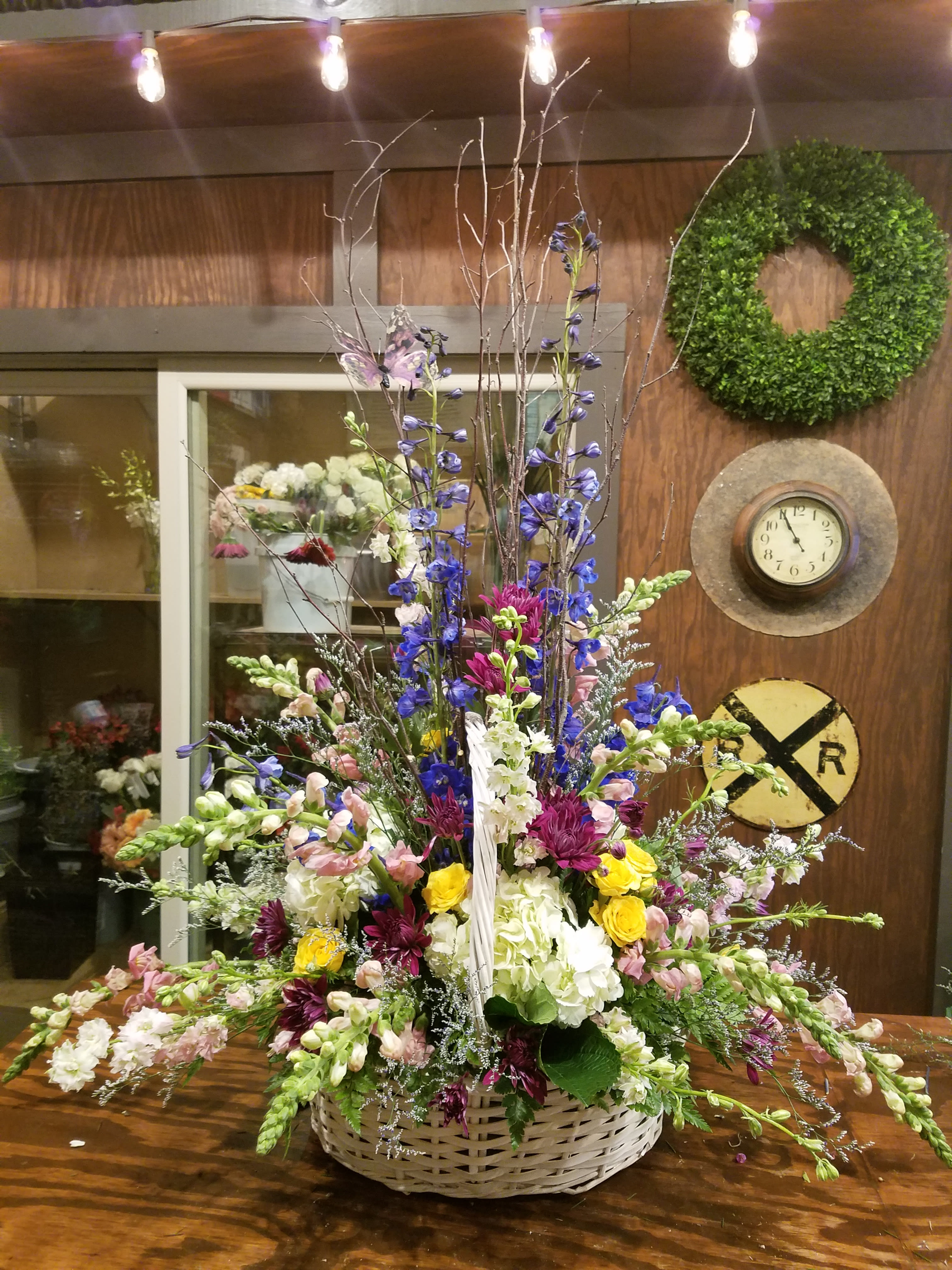 Large mixed flower arrangement in a wicker basket with tall branches