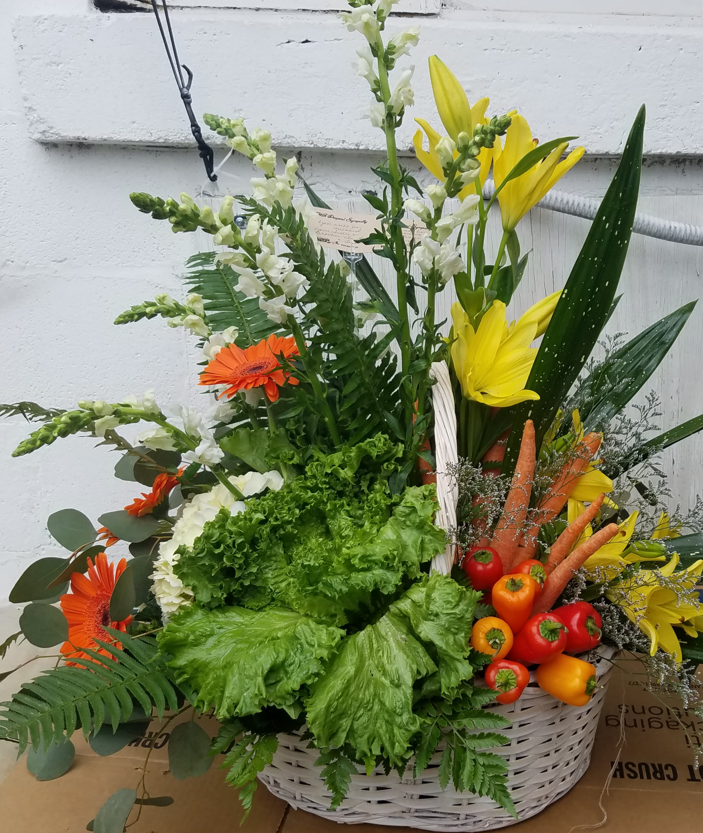 Basket arrangement with yellow lilies, orange gerberas, and vegetables