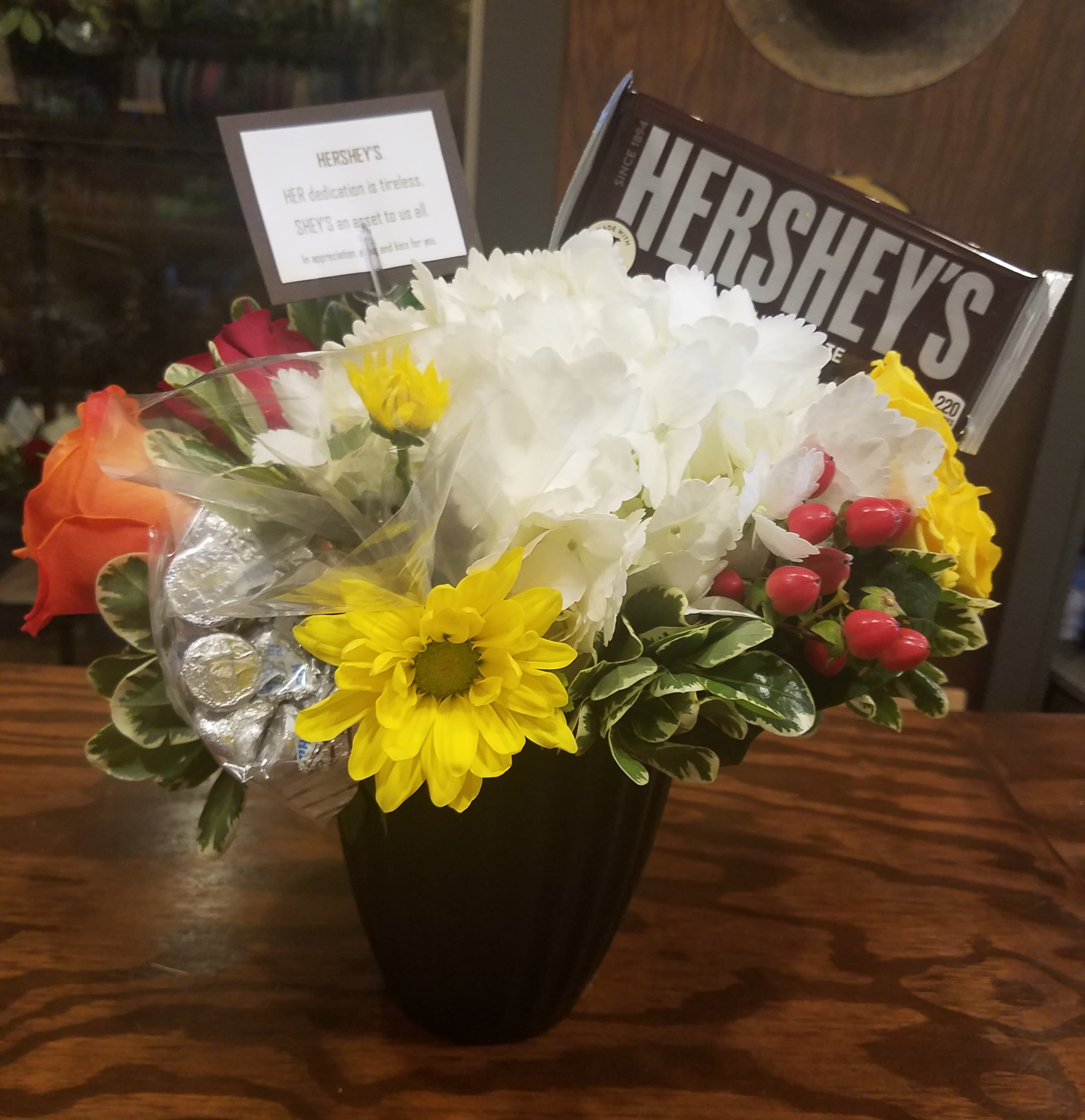 Bouquet of mixed flowers with a Hershey's chocolate bar in a black vase