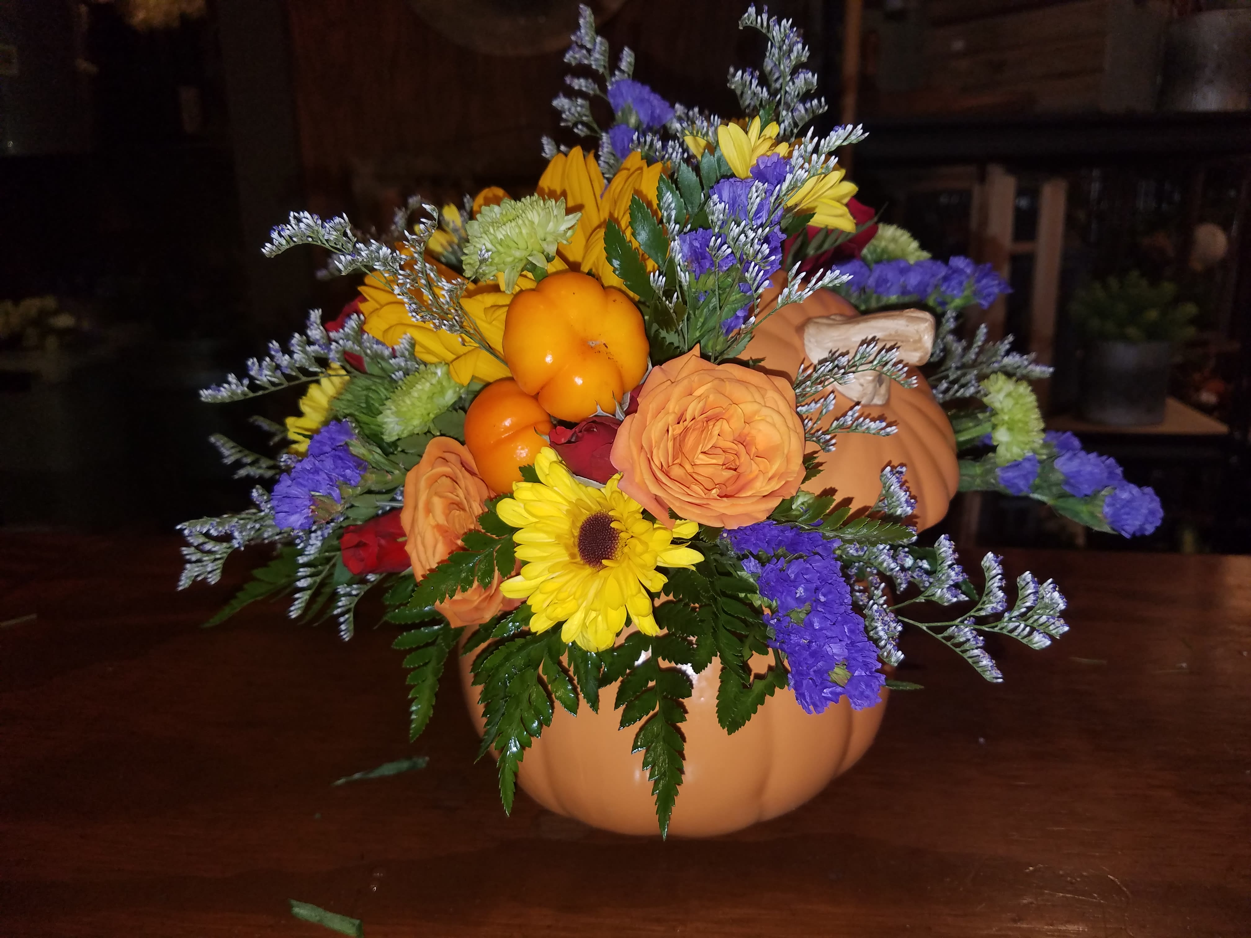 Fall floral arrangement in a pumpkin container with sunflowers and roses