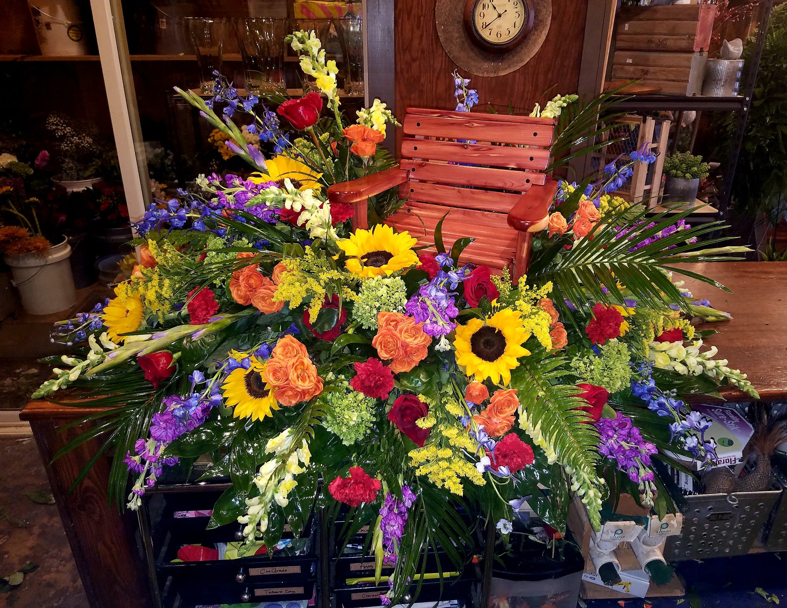 Large colorful floral arrangement with sunflowers and roses around a wooden chair