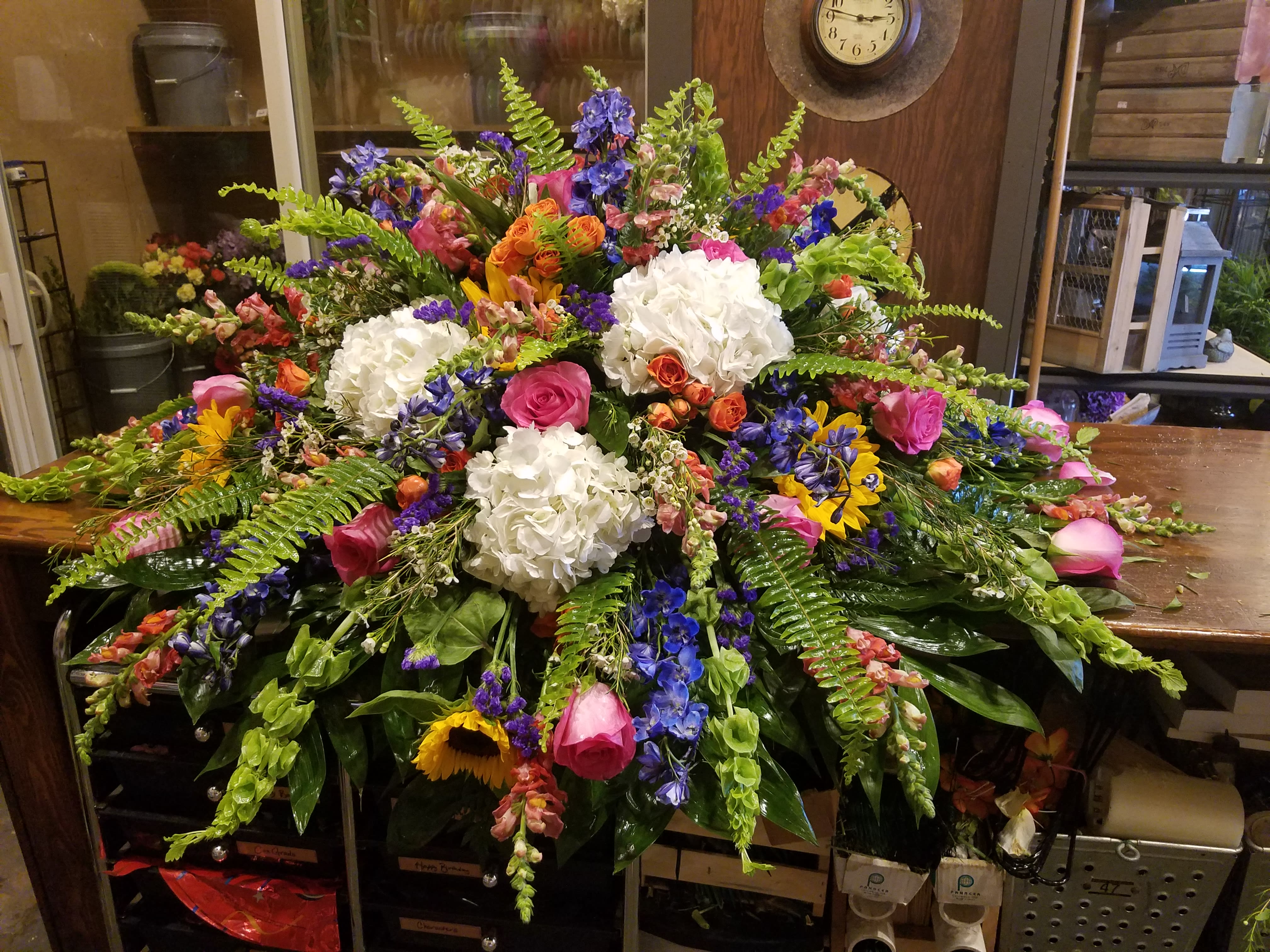 Large mixed floral arrangement with white hydrangeas, pink roses, and blue flowers
