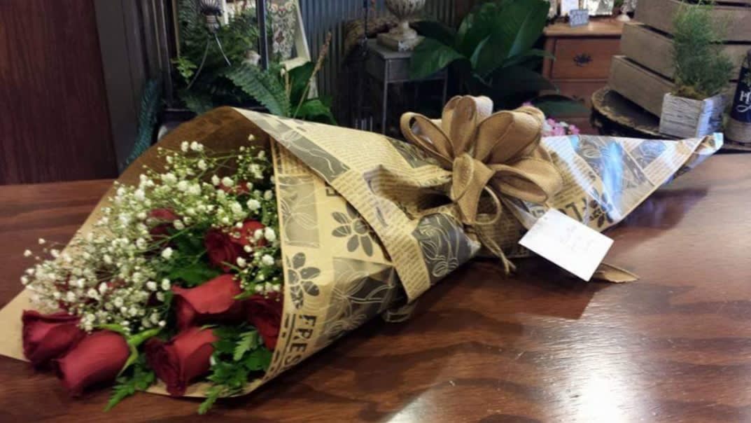 Bouquet of red roses and baby's breath wrapped in brown paper with a ribbon