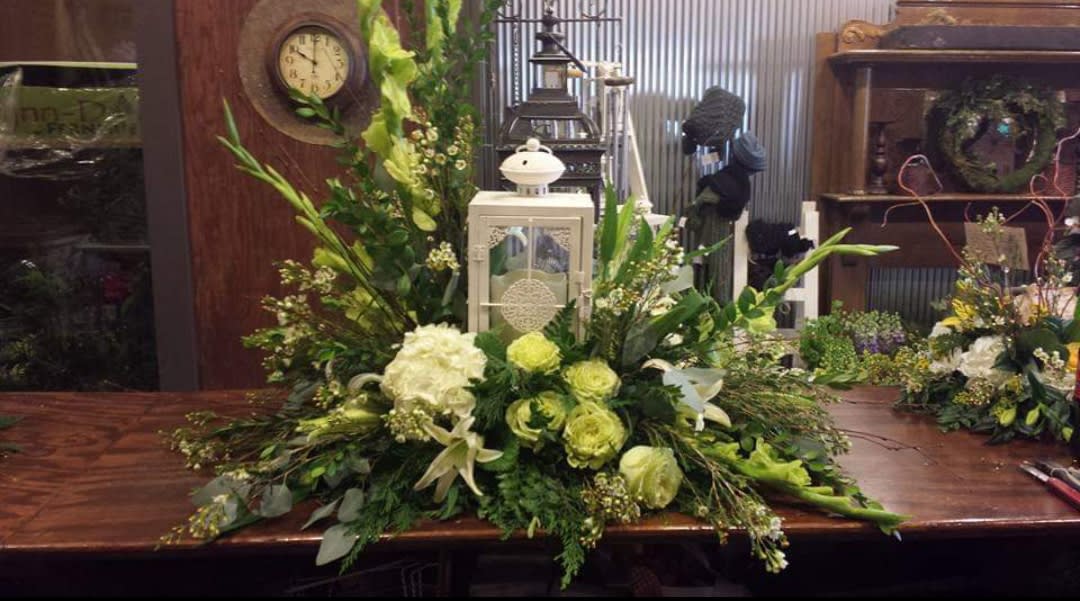 Large green and white floral arrangement with a lantern centerpiece