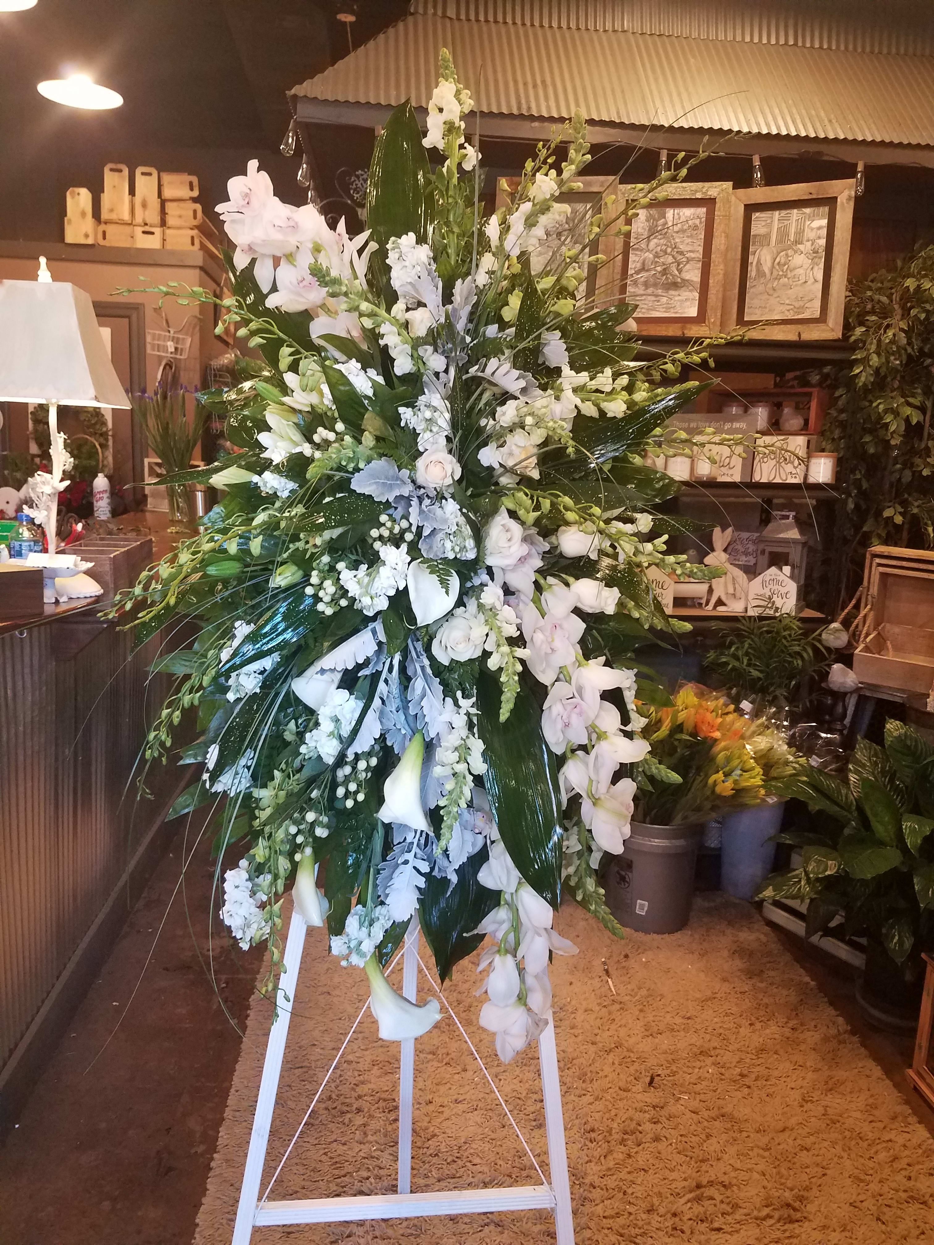 Tall white floral standing spray on a white easel