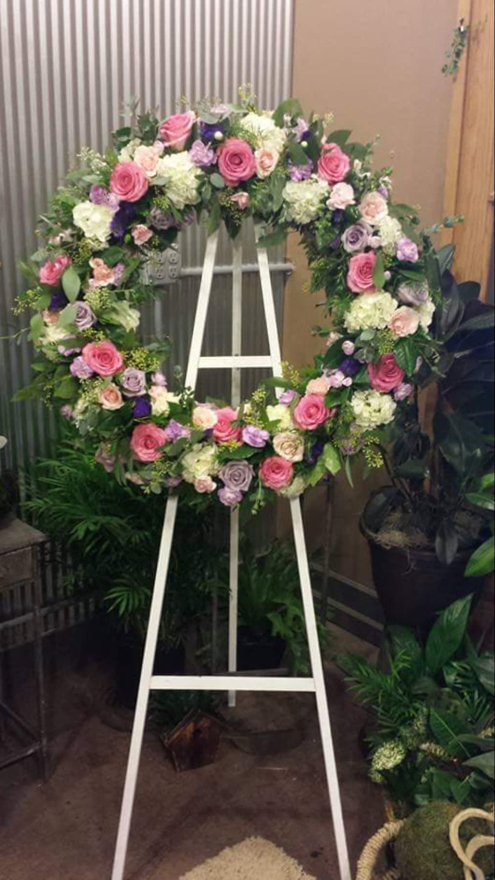Large floral wreath on a white easel with pink, white, and purple flowers