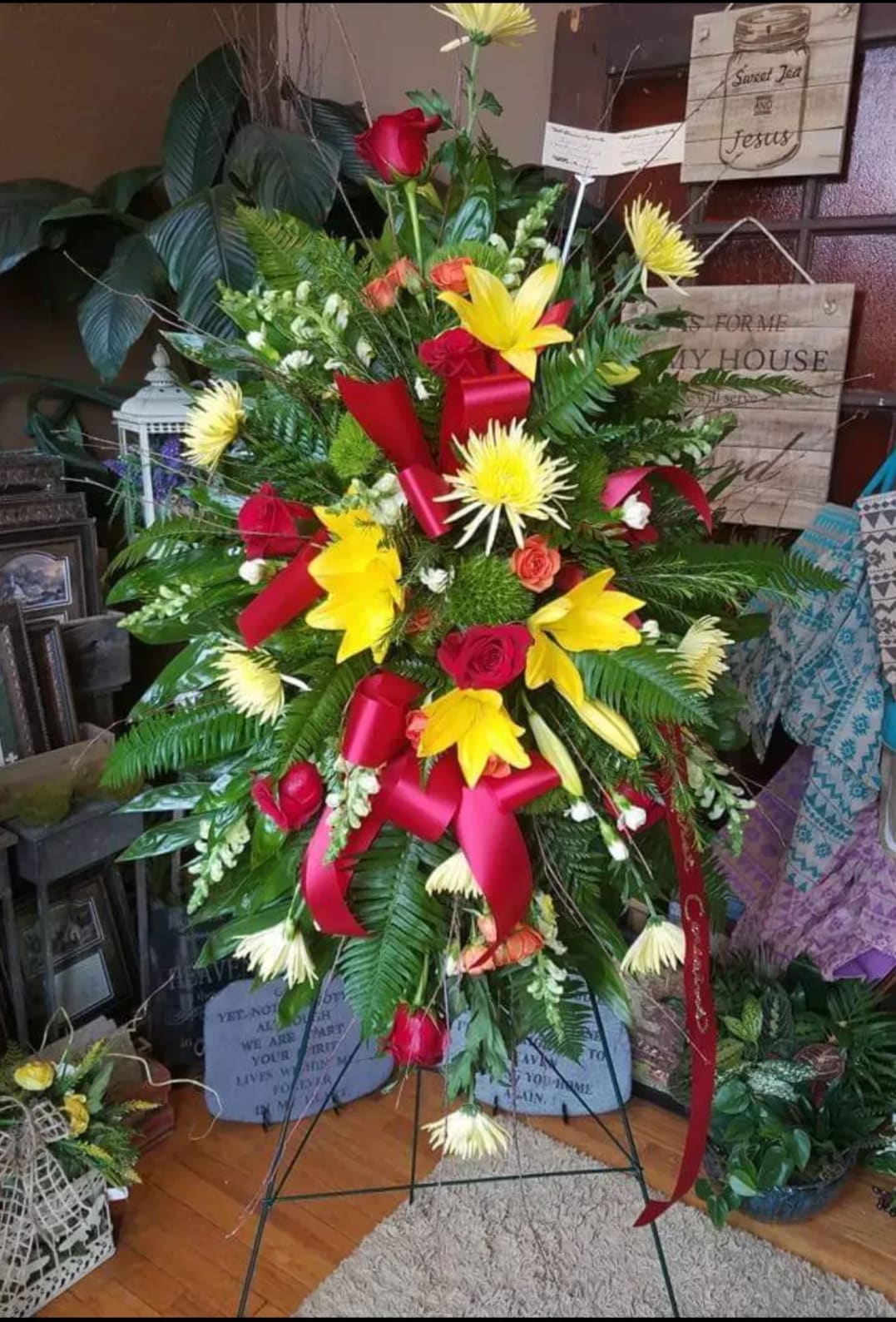 Sunset spray - A bright spray with an assortment of flowers that feature yellow lilies. This spray is on a medium size 54" easel. The upgraded prices reflect larger stands and more flowers added.  