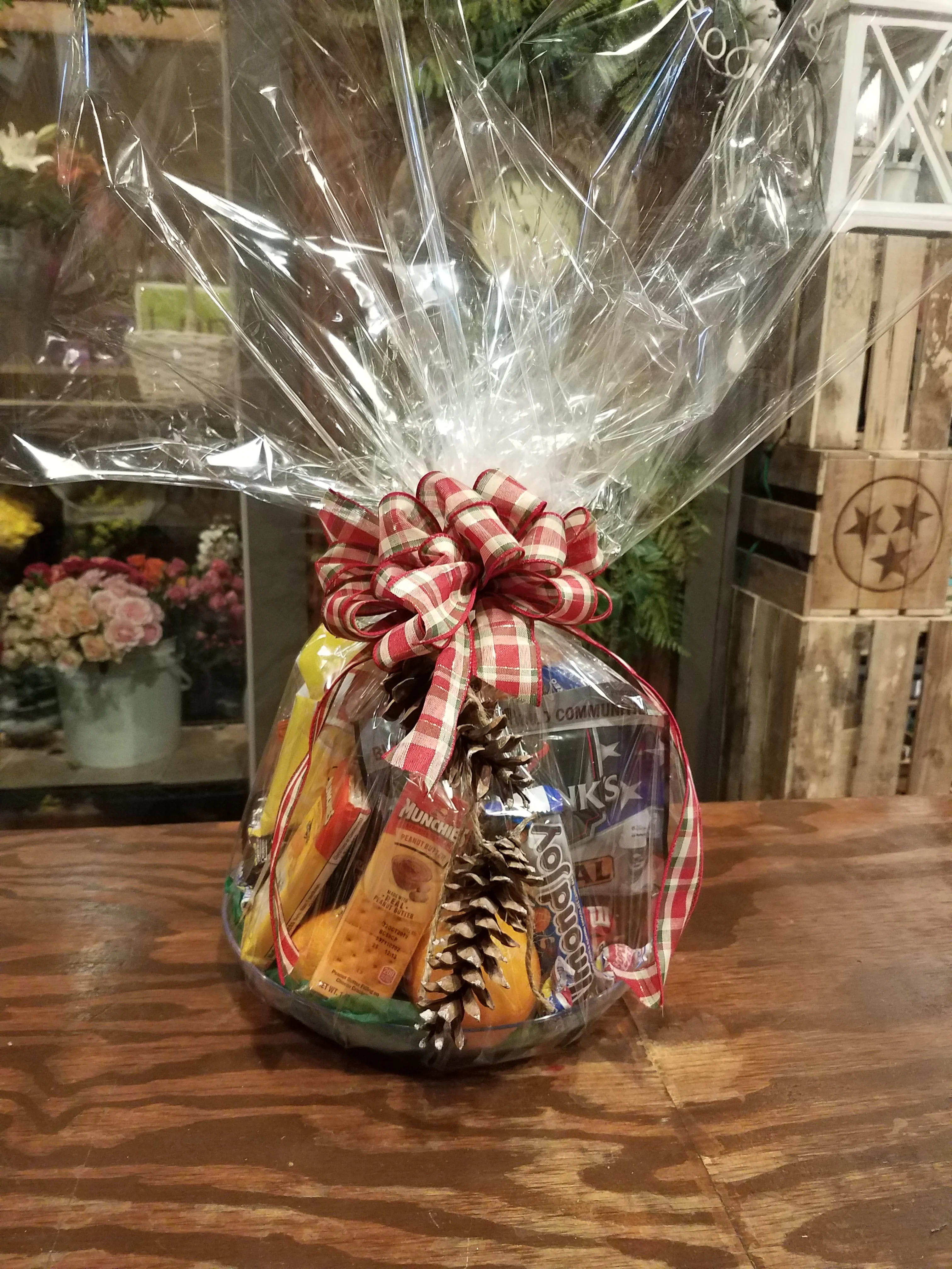 Gift basket of snacks wrapped in clear cellophane with a red plaid bow