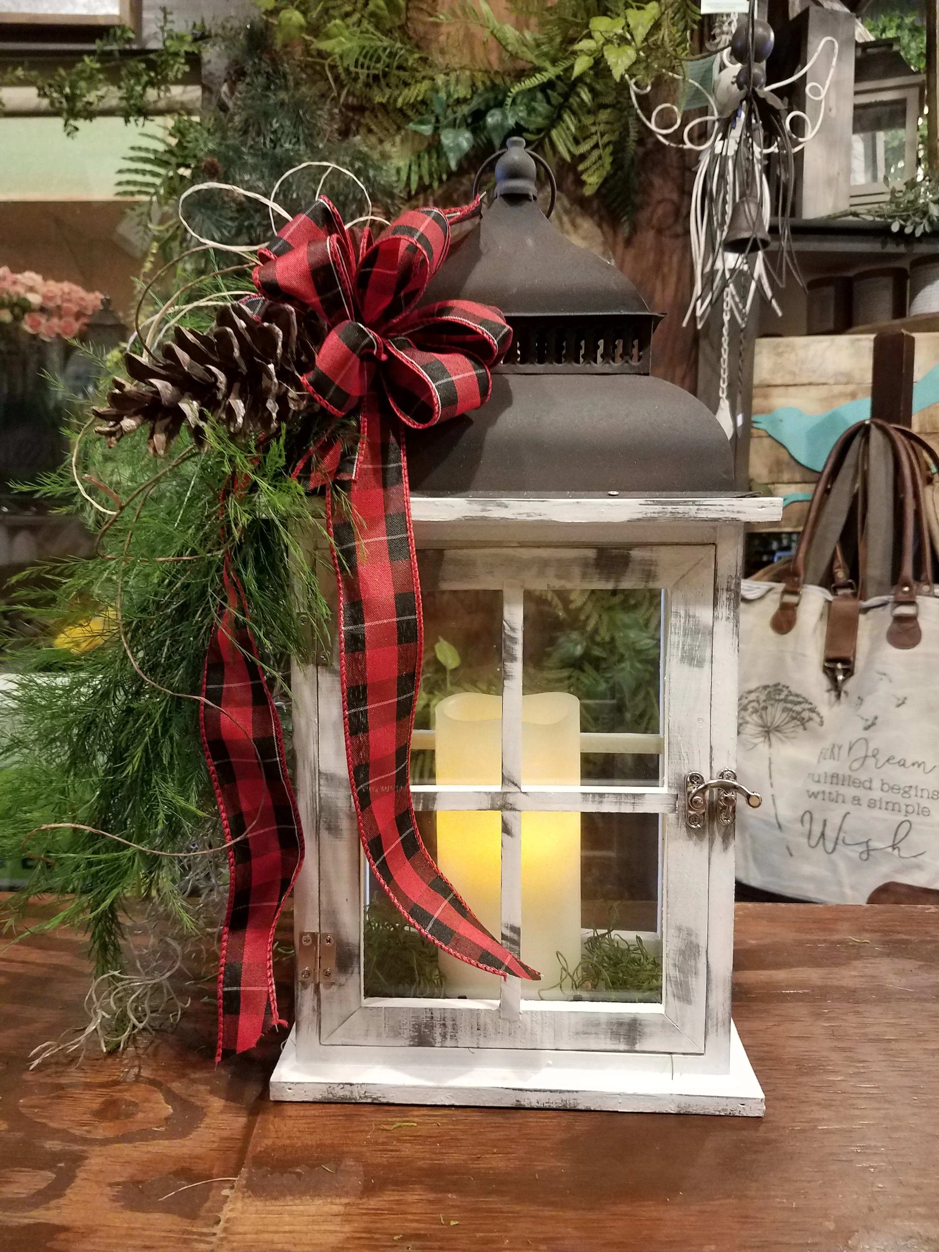 Decorative lantern with a plaid bow, pinecone, and greenery