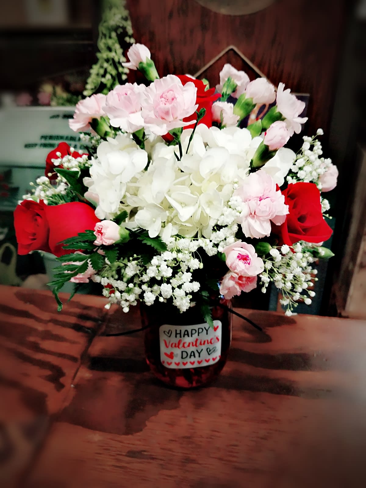 Bouquet of red roses, pink carnations, and white hydrangea in a vase