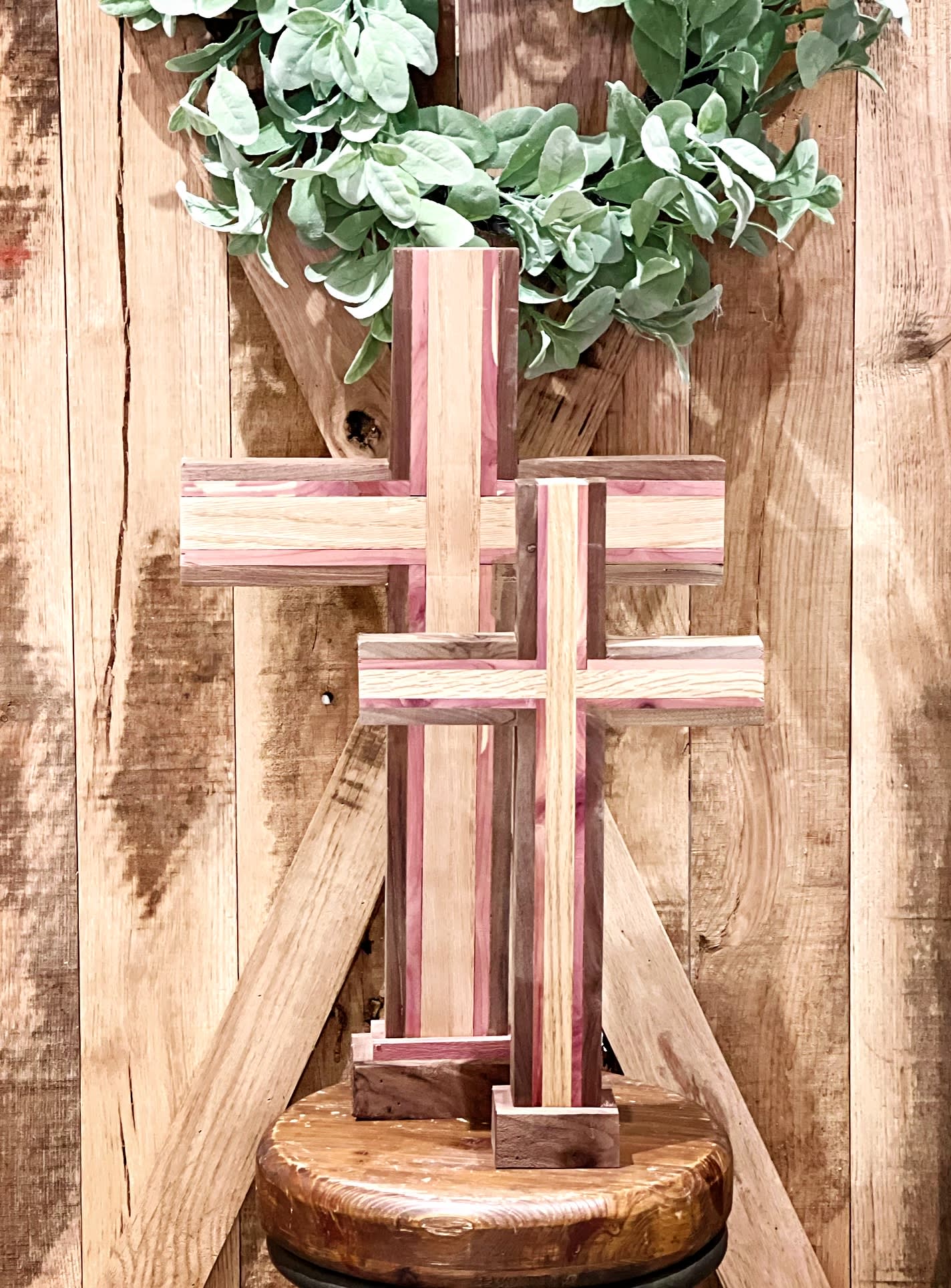 Wooden cross display with green foliage on a rustic wood backdrop