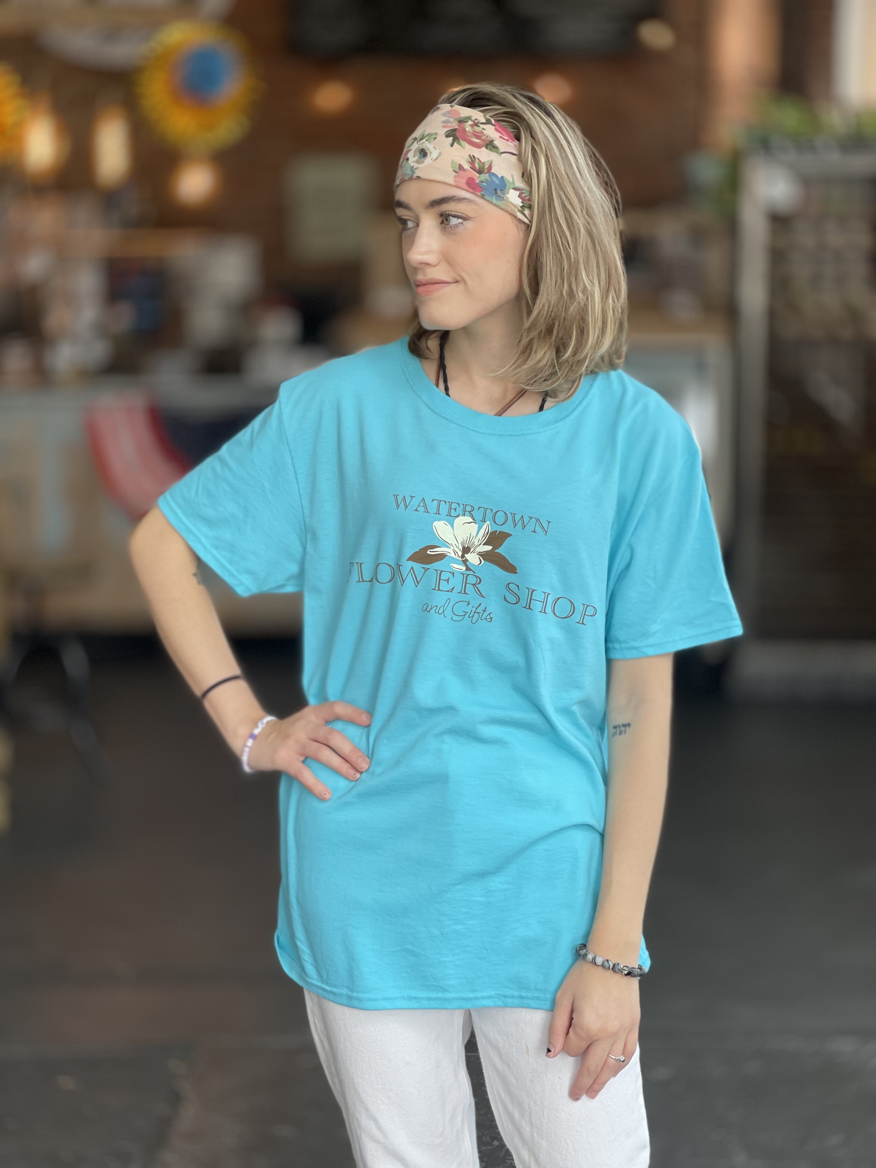 Woman wearing a turquoise flower shop T-shirt and floral headband