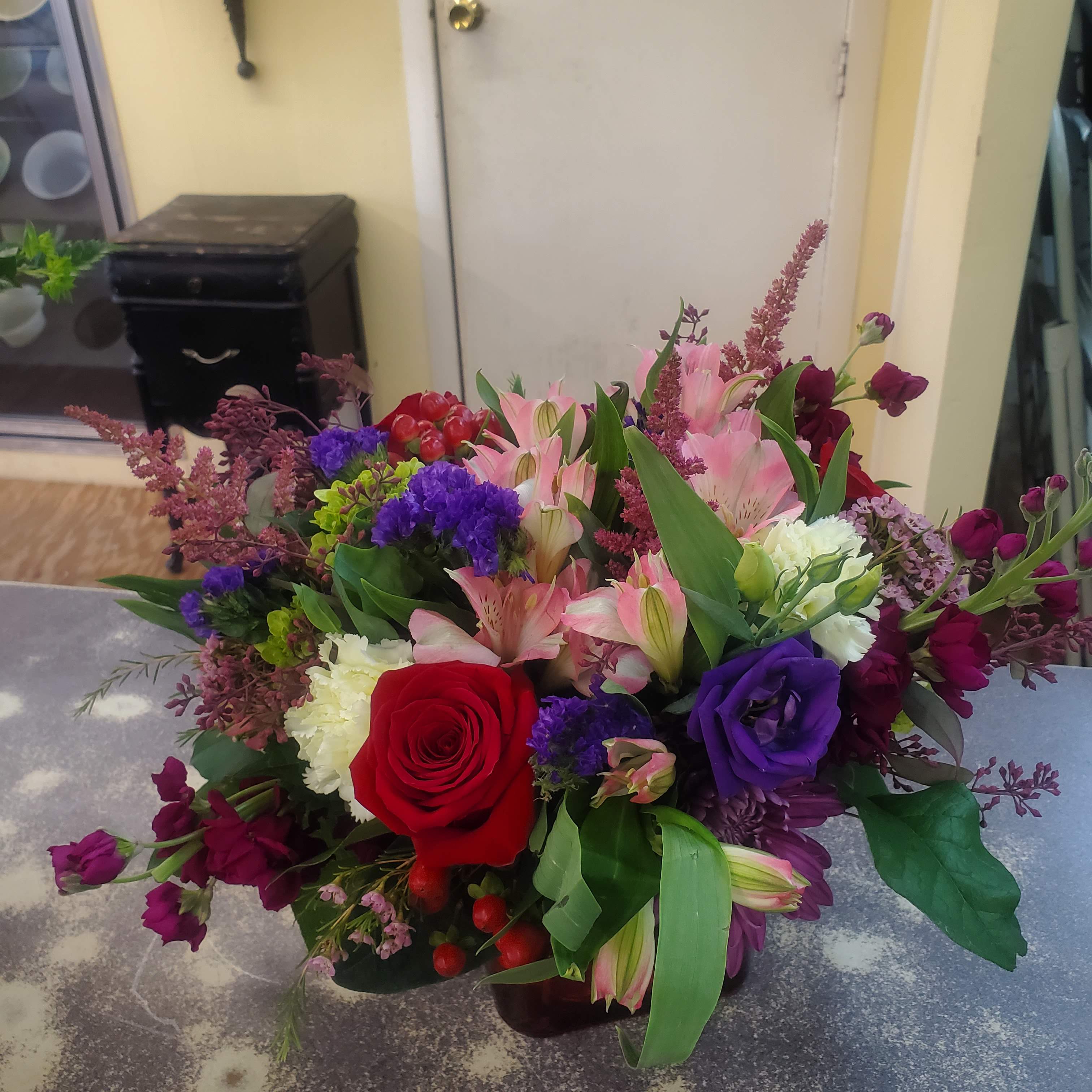 Mixed bouquet with red rose, pink lilies, and purple flowers in a vase