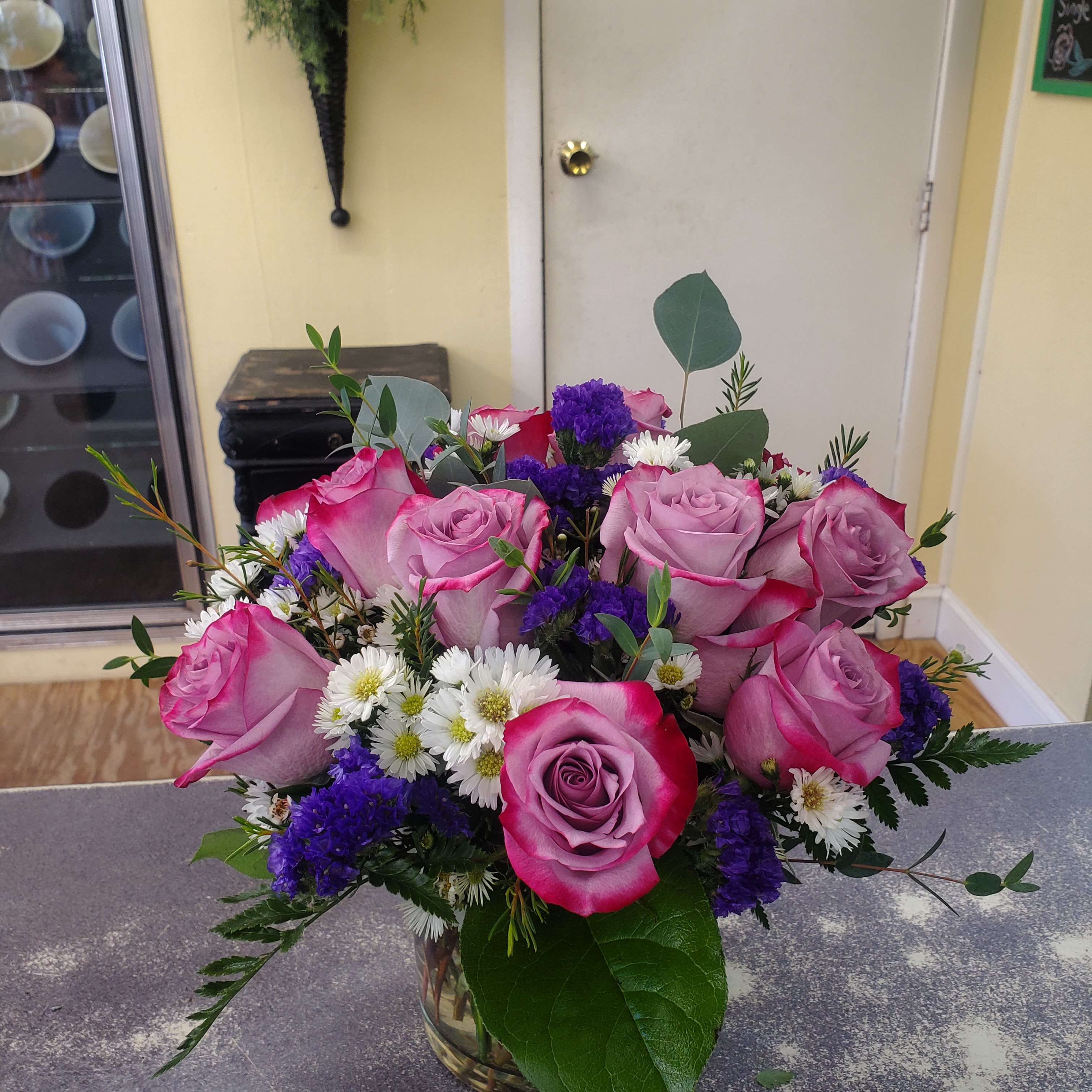 Pink roses with white daisies and purple filler in a glass vase