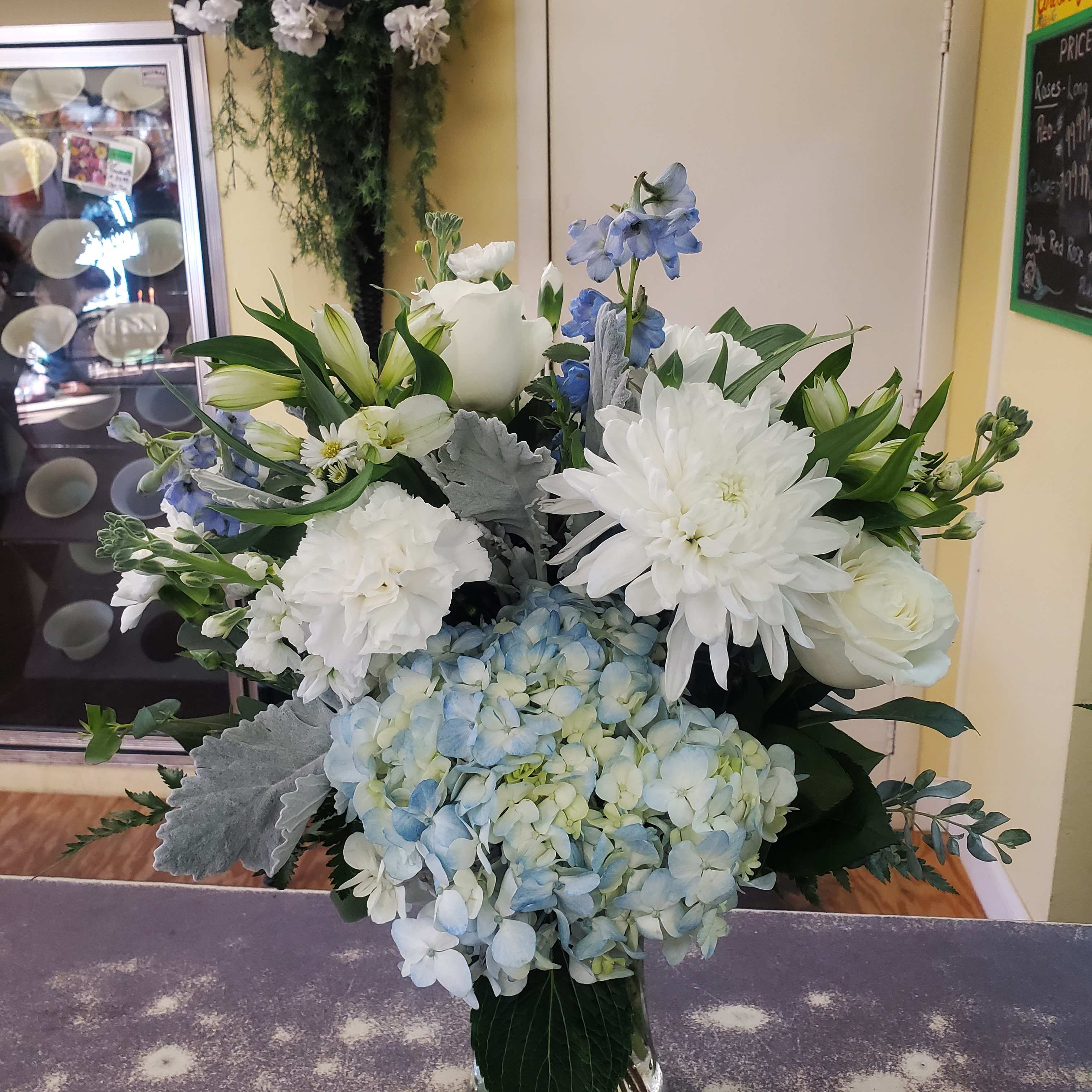 White and blue floral arrangement in a glass vase