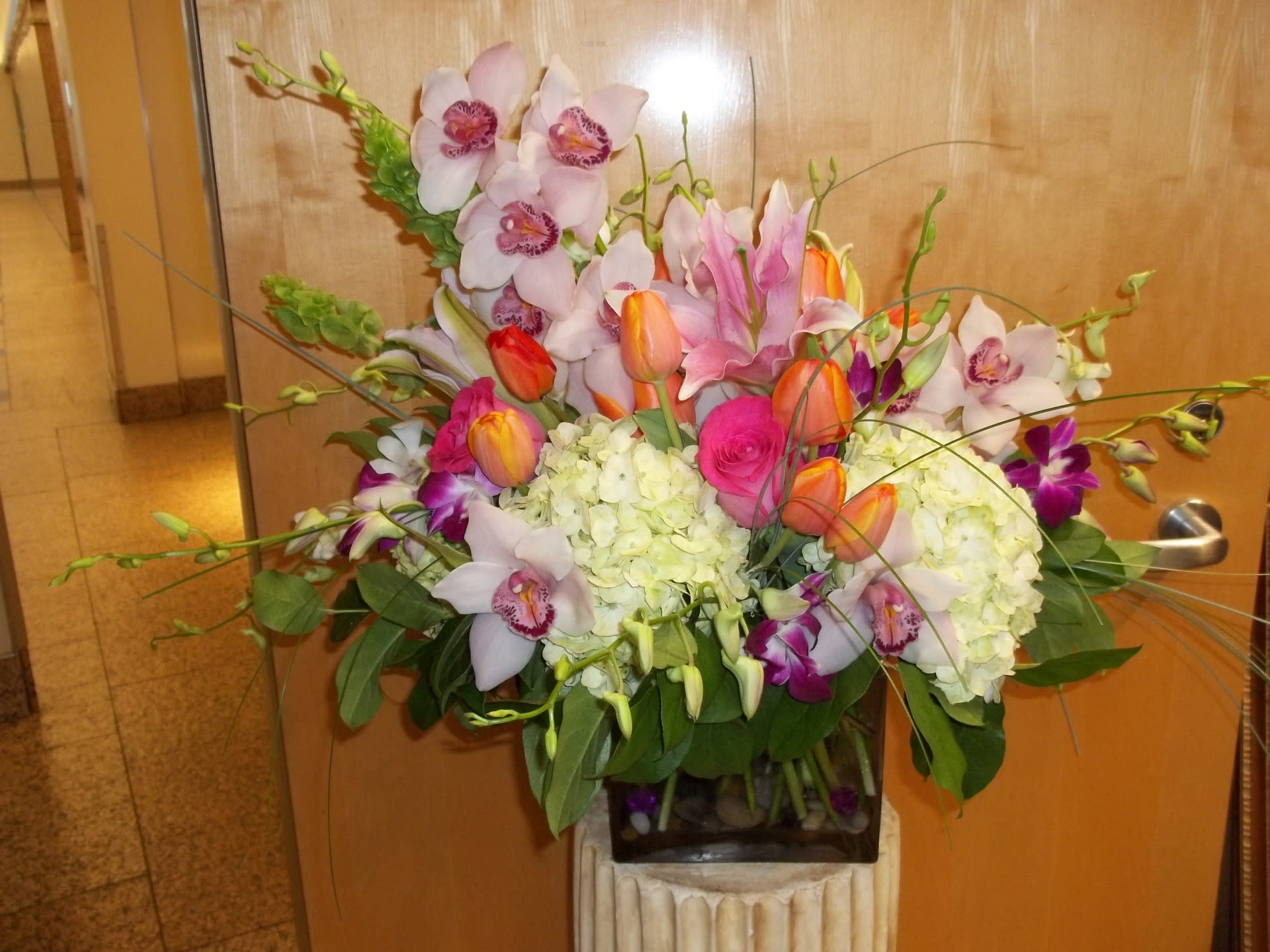 Mixed bouquet with orchids, tulips, hydrangeas, and roses in a vase