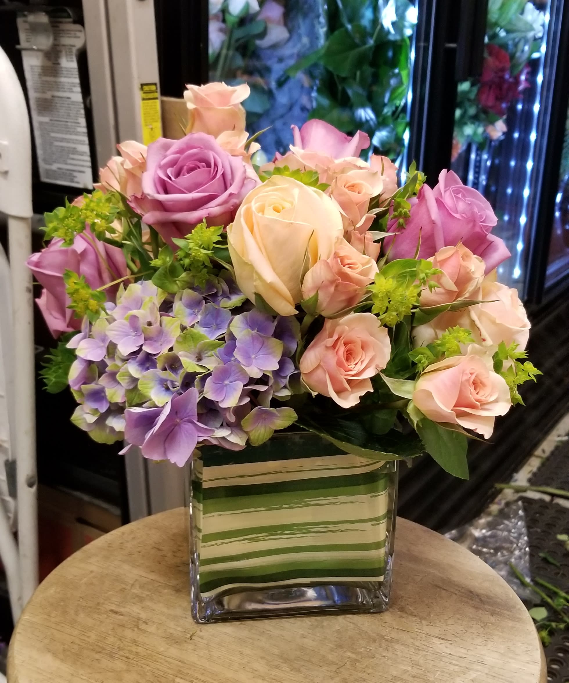 Bouquet of pink and lavender roses with purple hydrangea in a glass vase
